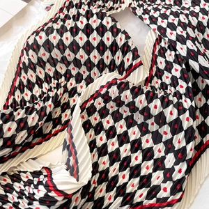 Détail d'une écharpe plissée avec damier noir et blanc et motifs de cœurs rouges