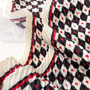 Détail de la texture plissée d'un foulard en soie avec damier noir et blanc et motifs cœurs