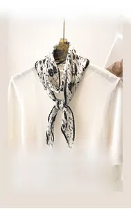 Détail d'un foulard plissé blanc à fleurs sur le col d'un pull en maille blanc
