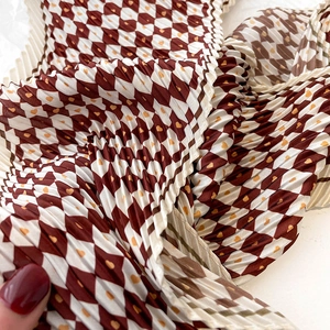 Gros plan d'un foulard plissé en soie avec motif losanges rouges et petits cœurs