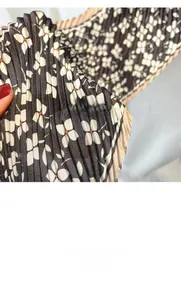 Close-up of pleated floral scarf fabric with wavy edges and small white blossoms