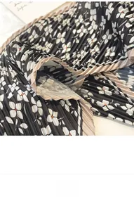 Detail of floral pleated scarf fabric featuring black and white patterns with hemmed edges