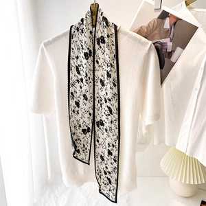 Gros plan d'un foulard plissé blanc à fleurs noires sur un pull en maille blanc