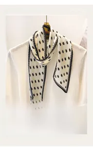 Detailed view of cream pleated scarf with large black polka dots and fine edge stitching