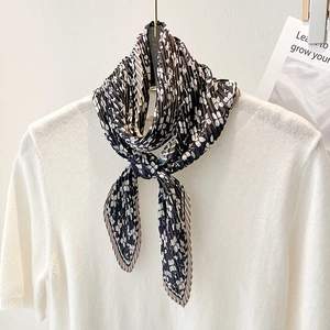 Floral pleated scarf with white small flower pattern on black fabric styled on a white shirt