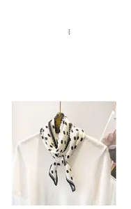 Detailed view of the wavy pleated texture and black polka dot pattern on the silk scarf