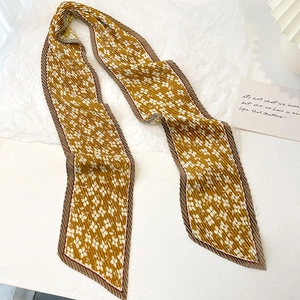 Detail of pleated floral skinny scarf in ginger yellow with small white flower patterns