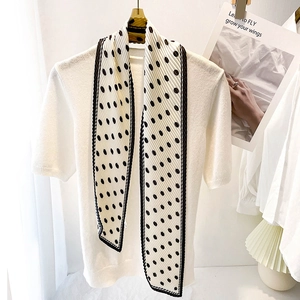 Detailed texture of white pleated scarf with black polka dots and fine knit top