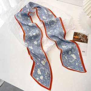 Détail du foulard plissé à fleurs bleu clair avec bordure orange contrastée