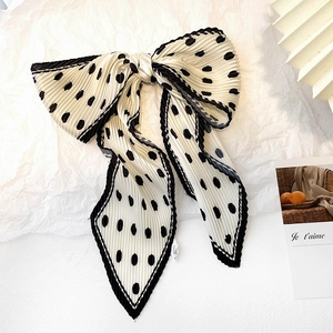 French style polka dot pleated silk scarf tied in a bow on a minimalist background