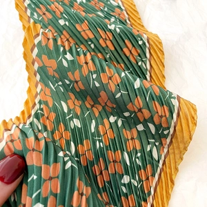 Detail of vintage floral pleated scarf with dark green print and yellow ruffled edges