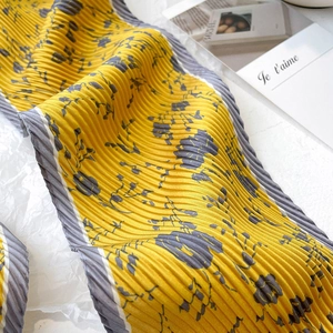 Gros plan sur l'écharpe plissée jaune vif avec imprimé fleuri et bordure à rayures
