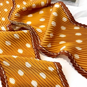 Macro detail of mustard yellow pleated polka dot scarf with white dot texture