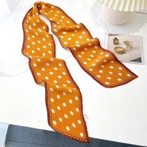 Detail of a bright yellow pleated polka dot scarf used as a stylish bag accessory