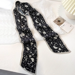 Détail d'un foulard plissé noir avec imprimé floral blanc et bords rayés élégants