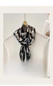 Detail of diamond pattern pleated silk scarf tied on a white knitted sweater