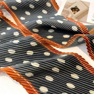 Macro detail of navy blue polka dot pleated silk scarf with contrasting orange edges