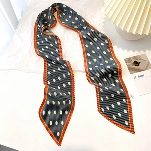 Detailed close-up of dark grey pleated silk scarf with white polka dots and orange border