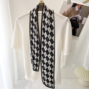 Close-up of black and white checkerboard pleated silk scarf on a white knit shirt