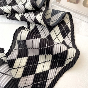 Close-up of diamond checkered scarf featuring refined accordion pleats and grey tones