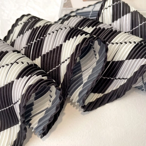 Close-up of pleated argyle pattern silk scarf with elegant black and white diamond texture
