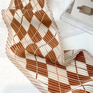Macro shot of brown and white checkered pleated scarf showing rich fabric texture