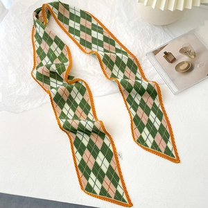 Detail of pleated silk scarf featuring green and pink diamond pattern with orange borders