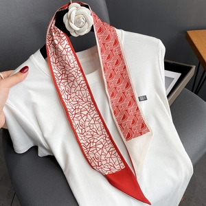Détail d'un foulard twilly géométrique rouge et blanc orné d'une fleur de camélia