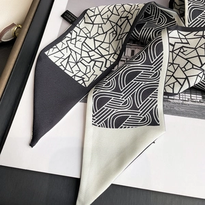 Détail du foulard twilly à motif géométrique montrant la texture et l'étiquette