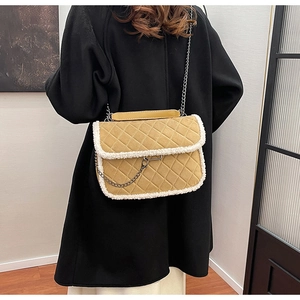 Détail du sac matelassé jaune avec bordure en fausse fourrure blanche porté sur un manteau