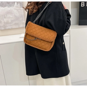 Détail d'un sac matelassé marron avec chaîne mate et bordure en polaire sur l'épaule