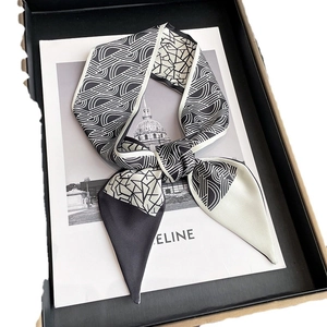 Écharpe étroite en soie géométrique noir et blanc nouée sur un coffret cadeau élégant