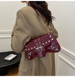 Détail du sac en cuir verni bordeaux avec rivets argentés et boucle punk sur mannequin