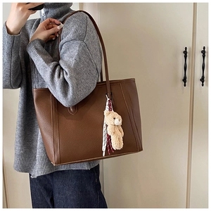 Dettaglio della borsa tote in pelle litchi marrone con ciondolo a orsetto