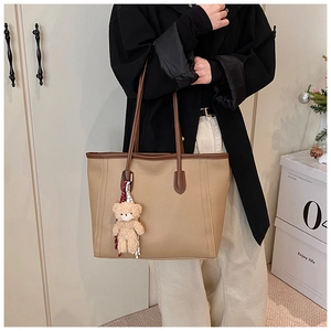 Dettaglio della borsa tote in pelle kaki con ciondolo a forma di orso e manici marroni