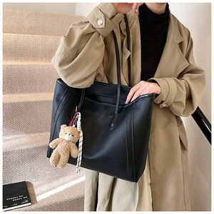 Dettaglio borsa tote in pelle nera a grana litchi con ciondolo a forma di orsetto di peluche