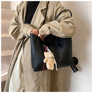 Dettaglio borsa tote in pelle martellata nera con ciondolo a forma di orsetto marrone