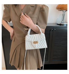 Weiße gesteppte Handtasche mit goldenem Drehverschluss in einer Lifestyle-Umgebung