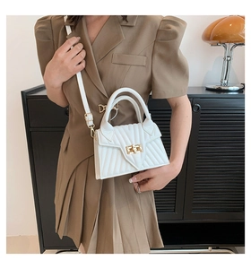 Weiße Stepptasche mit goldenem Drehverschluss kombiniert mit modischem braunem Anzug
