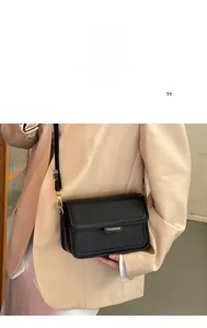 Détail du sac bandoulière noir en cuir grainé avec plaque logo en métal doré