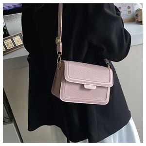 Détail de la texture cuir grainé rose du petit sac bandoulière et métal doré
