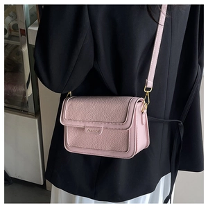 Détail du sac bandoulière rose avec cuir à grain litchi et boucles en métal doré