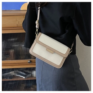 Détail du sac bandoulière en cuir crème avec bordure kaki et garniture dorée