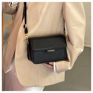 Détail d'un sac bandoulière en cuir grainé noir avec plaque logo FASHION dorée