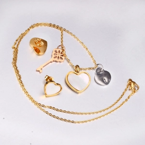 Detail of gold heart pendant necklace with mother of pearl and silver lock charm