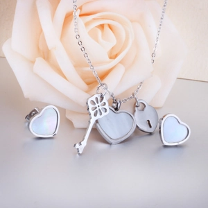 Detail view of heart necklace and studs set with white shell inlay and key pendant