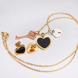 Detail of heart pendants with key and lock on gold chain and matching studs