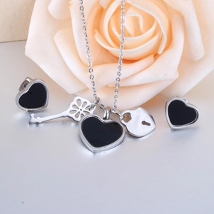 Silver jewelry set with black heart pendants and key charms shown with a rose