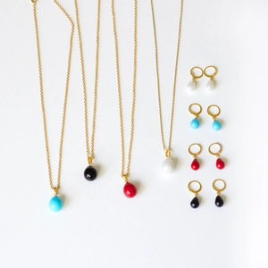 Detail view of drop-shaped shell pearl necklace and earrings set in four colors