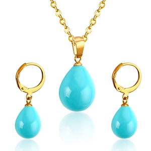 Close-up of gold drop necklace and leverback earrings with blue teardrop stones